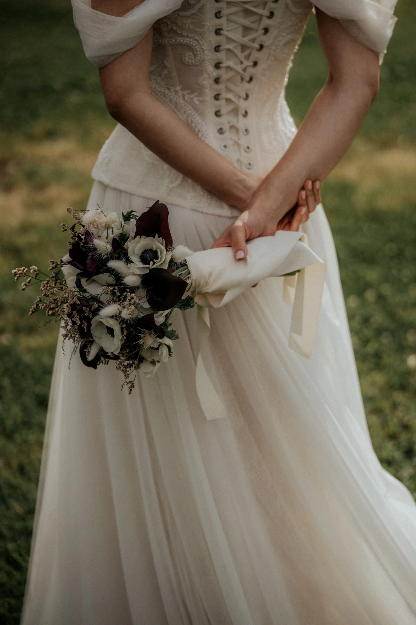 Le mani e il bouquet dietro l’abito