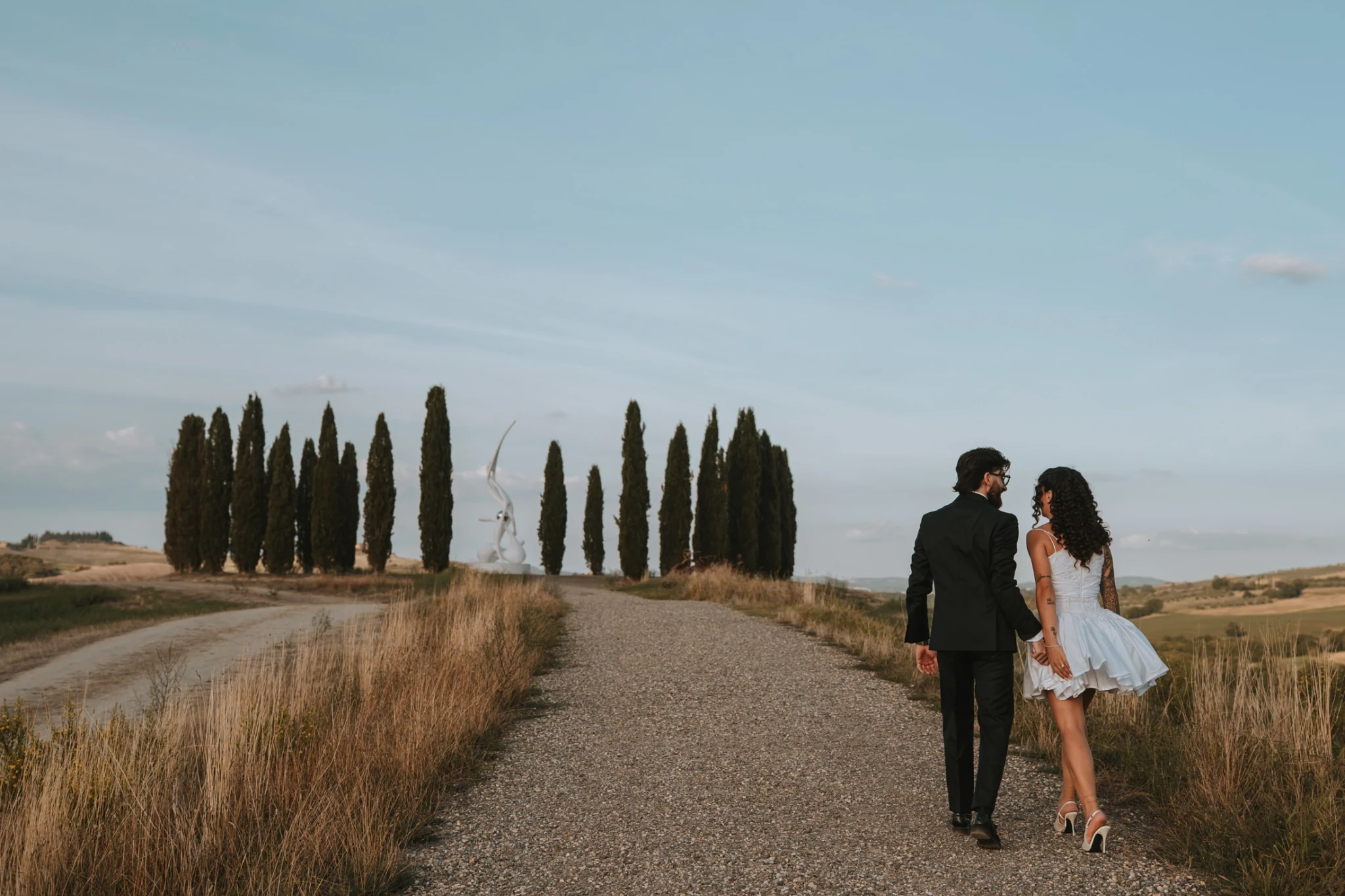 Gli sposi camminano verso il viale di cipressi