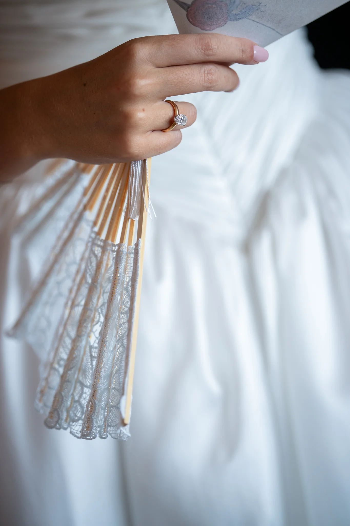 Un dettaglio dell’abito bianco e delle mani della sposa
